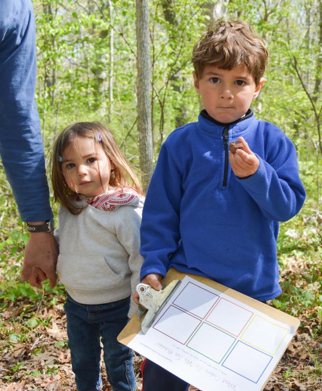 James Brum holds up a red rock he uncovered in the woods while his sister, Adelyn, looks on. BY SETH THOMAS