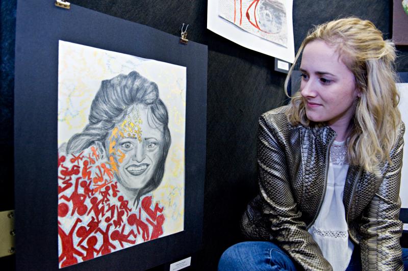 Senior Catherine George poses with a portrait of her mother called “Over Extended." BY DOLLY GENANNT