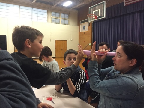 Fourth-grader Jake Melo, third-grader Tiago Lameiro, and Rute Lameiro use construction paper to create the optical illusion of a hole going through their hand. BY ANGIE HILSMAN
