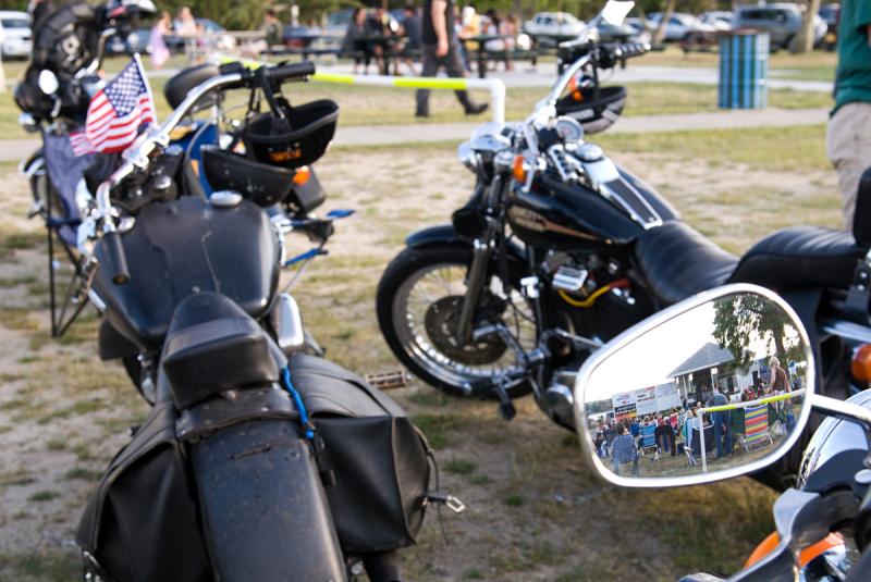 The band is seen playing in the mirror of one of the many motorcycles parked on the property. BY DOLLY GENANNT