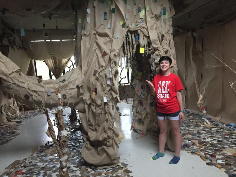 Serena Turner stands beside the installation she worked on, titled "A Walk in the Canopy." BY ANGIE HILSMAN