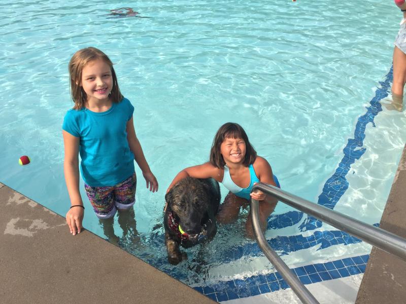 Elena Sobran (left) and Abby Glaser (right) hug Barkley as he comes out of the water. BY ANGIE HILSMAN