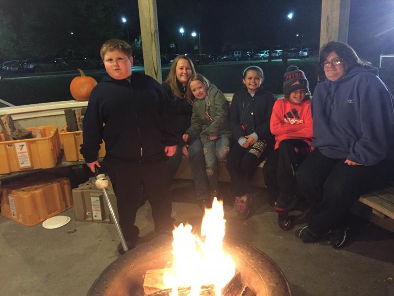 Christopher Medeiros, Kristen Hutchins, Keira Hutchins, Lillian Doherty, Brennan Carter, and Alyson Doherty keep warm around an open fire. BY ANGIE HILSMAN