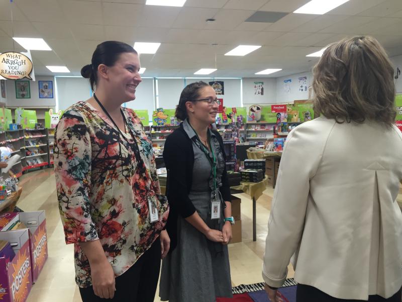 Assistant Principal Audra Thomas and Librarian Kate Powers show Lauren Baker the book sale. BY ANGIE HILSMAN