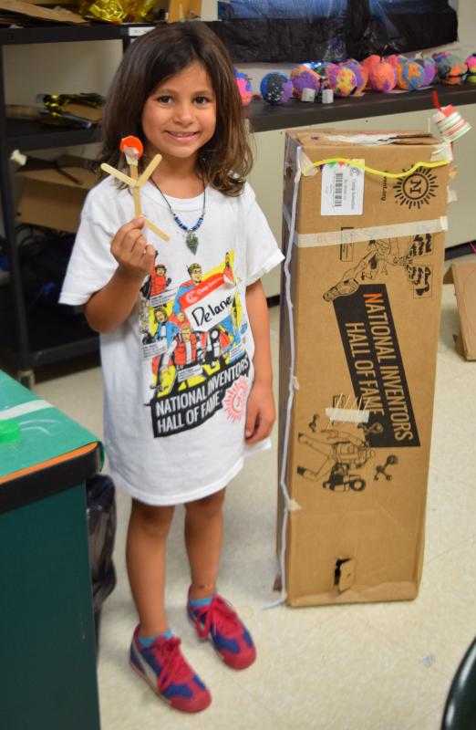 Delaney Ferrick shows a stick figure and mock house her group built for their planet. BY DOUGLAS MCCULLOCH