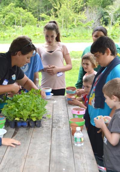 Sarah Cogswell helps Junior Grange members plant some greenery in their freshly painted pots. BY SETH THOMAS