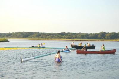 Volunteers and interns prepare to scoop the ducks out of the water as they funnel through a small opening in the finish line. BY SETH THOMAS