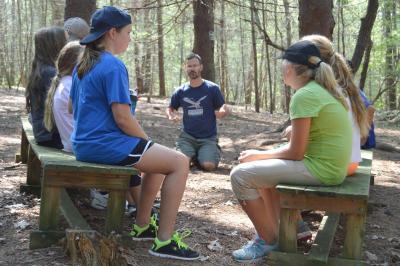 Charley Pelissier (background), director of external programs at Friends Academy, preps students for the ropes course. BY SETH THOMAS