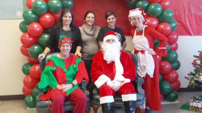 (Back row) Lisa Perry, Jessica Couto, Sonya Silva and Stephanie Yermalovich. (Front row) Principal Colin Grimsey and Kyle Yermalovich as Santa Claus. BY MORGAN BANVILLE