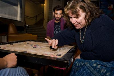 Linda Kent Davis tests her skill in the Indian game Carrom while Prati Bhansau watches. The game is similar to pool. BY DOLLY GENANNT