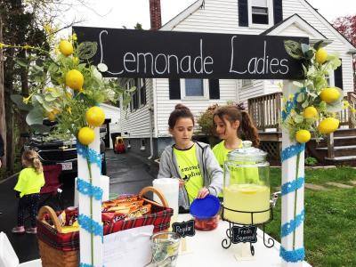 Ten-year-old Madalen Williams (left) and Cassie Sommer (9) adding fresh strawberries to a customer’s lemonade. Photo by: Kate Robinson