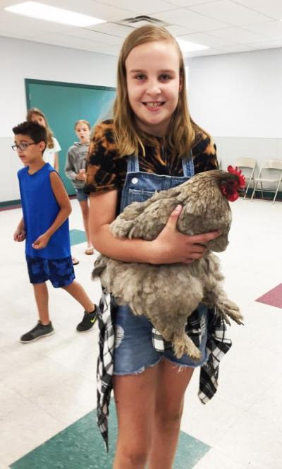 Addison Thompson, 10, holds her favorite hen, Country, a cochin chicken with feathered legs