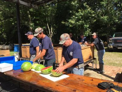 Firefighters cutting up some watermelon for dessert.