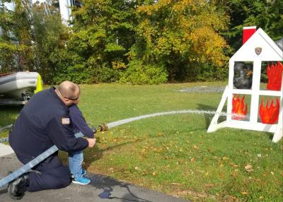 A firefighter helps a child with the fire hose at the open house.