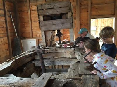 Students peer into the space where the running stone used to grind the grain inside the mill.
