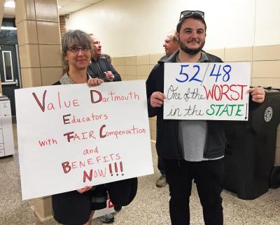 Two protesters holding signs outside the meeting, which took place at Quinn School.