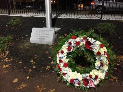 The new stone memorial underneath the flag pole, with a wreath nearby.