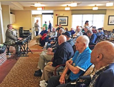Veterans and friends listen to musician Dave Manuel playing patriotic songs.