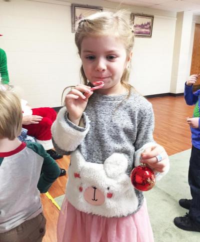 Dartmouth, MA news - Christmas at Southworth Library - Six-year-old Adriana Debarros munches on a candy cane while decorating the tree.