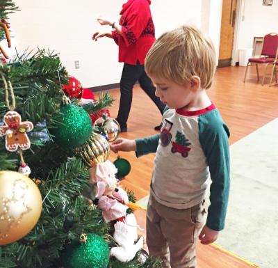Dartmouth, MA news - Christmas at Southworth Library - Three-year-old Luke Debarros of Dartmouth decorates the tree. He asked Santa for an orange and blue guitar for Christmas.