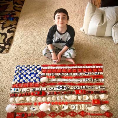 Lucien Bernard, 7, poses in front of a Patriots Day flag he created for a social studies assignment. Photo courtesy: Renee Monteiro-Bernard
