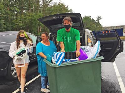 Dana Douglas (left) puts one last item into the bin wheeled by parents Cheryl and Jonathan before carting it to Spruce Hall.