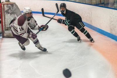 Bishop Stang junior forward Adyn Simmons and Dartmouth senior forward J.C. Frates chase the puck as it gets sent around the boards, almost giving one photographer a heart attack.