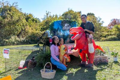 Left to right: Lynette Soler, Jessiah Ortiz, and Miguel Aguilar pose in front of their Jurassic World booth.