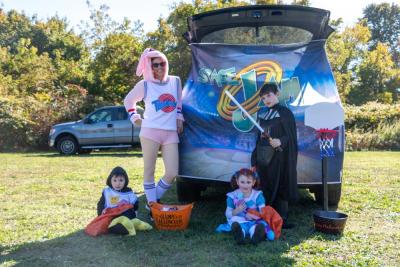 Melissa Lennox (Lola Bunny) and her kids Jonah (Daffy Duck), Scarlett (Poppy from Poppy Playtime), and Owen (Darth Vader) pass out candy at the trunk-or-treat.