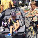 Levi Vieira, 4, sits in a stroller with three-month-old puppy Willow while his brother Tucker, 7, rides his bike
