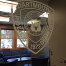 The Dartmouth Police logo on bulletproof glass in the administration area, with a spacious waiting area behind.