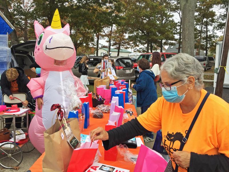 Carolyn Bussiere puts a raffle ticket into a bag as organizer Megan Bussiere oversees the table in her unicorn costume. Dartmouth Week - Dartmouth, MA news - Carolyn Bussiere puts a raffle ticket into a bag as organizer Megan Bussiere oversees the table in her unicorn costume.