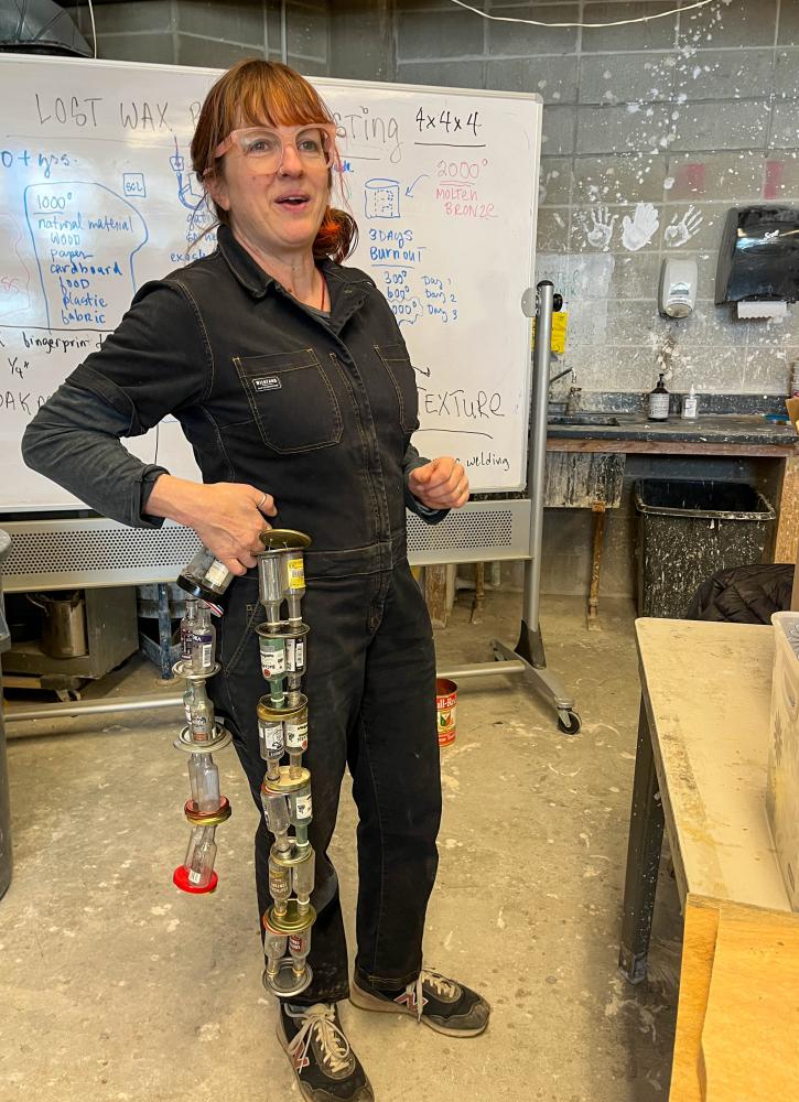 UMass Dartmouth’s visiting artist Rebecca McGee Tuck shows off a tail made from plastic bottles and bottle caps that the students will wear at the parade.