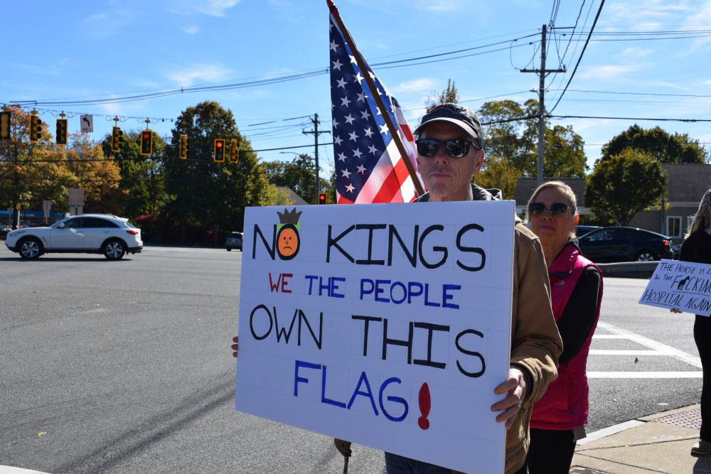 A man stands with his sign in front of the American flag. A man stands with his sign in front of the American flag.