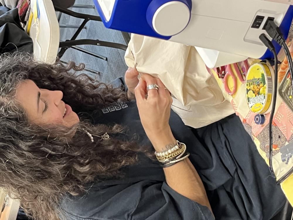 Photo of Claudia De Sousa Baptista mending clothing. Source: Marissa Perez Dormitzer