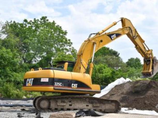 An excavator near a pile of contaminated soil at the former staging site on McCabe Street. Photo by Chris Shea