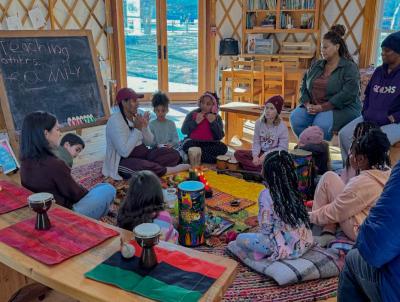 Kids gather around as Samia Walker as she teaches about Kwanzaa.