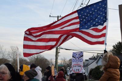 An American flag waves over a sign against I.C.E. Photos by Kat Sheridan
