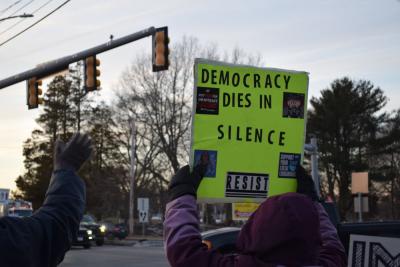 A sign calling for action held up to the road.