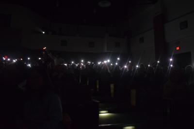 The crowd waves phone flashlights during a song.