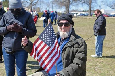 A man gives a thumbs up while holding the American flag.