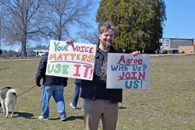 A man holds signs urging people to join.