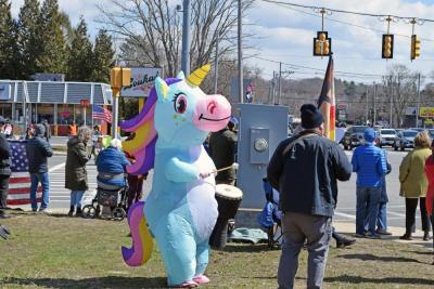 The rainbow unicorn for peace plays a drum.