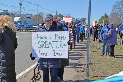 A protester holds a sign stating people are more powerful as a group.