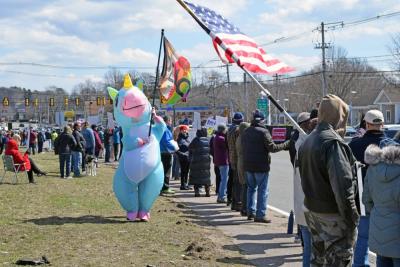 The rainbow unicorn for peace waves her peace flag.