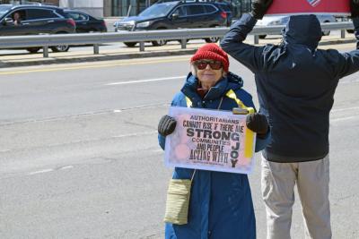 A woman shows her sign asking for joyful protest.