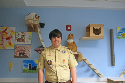 Zane Moriarty poses with the cat wall he helped build. 