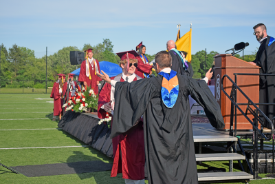 A student and a member of staff celebrate after the student received his diploma. 