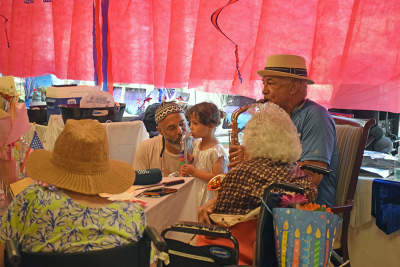 Gene Monteiro plays the saxophone for his aunt, while his granddaughter 'plays' alone. 