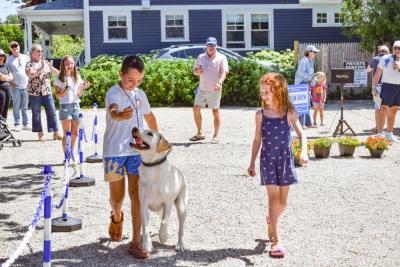 Two kids walk Rosie the lab. 